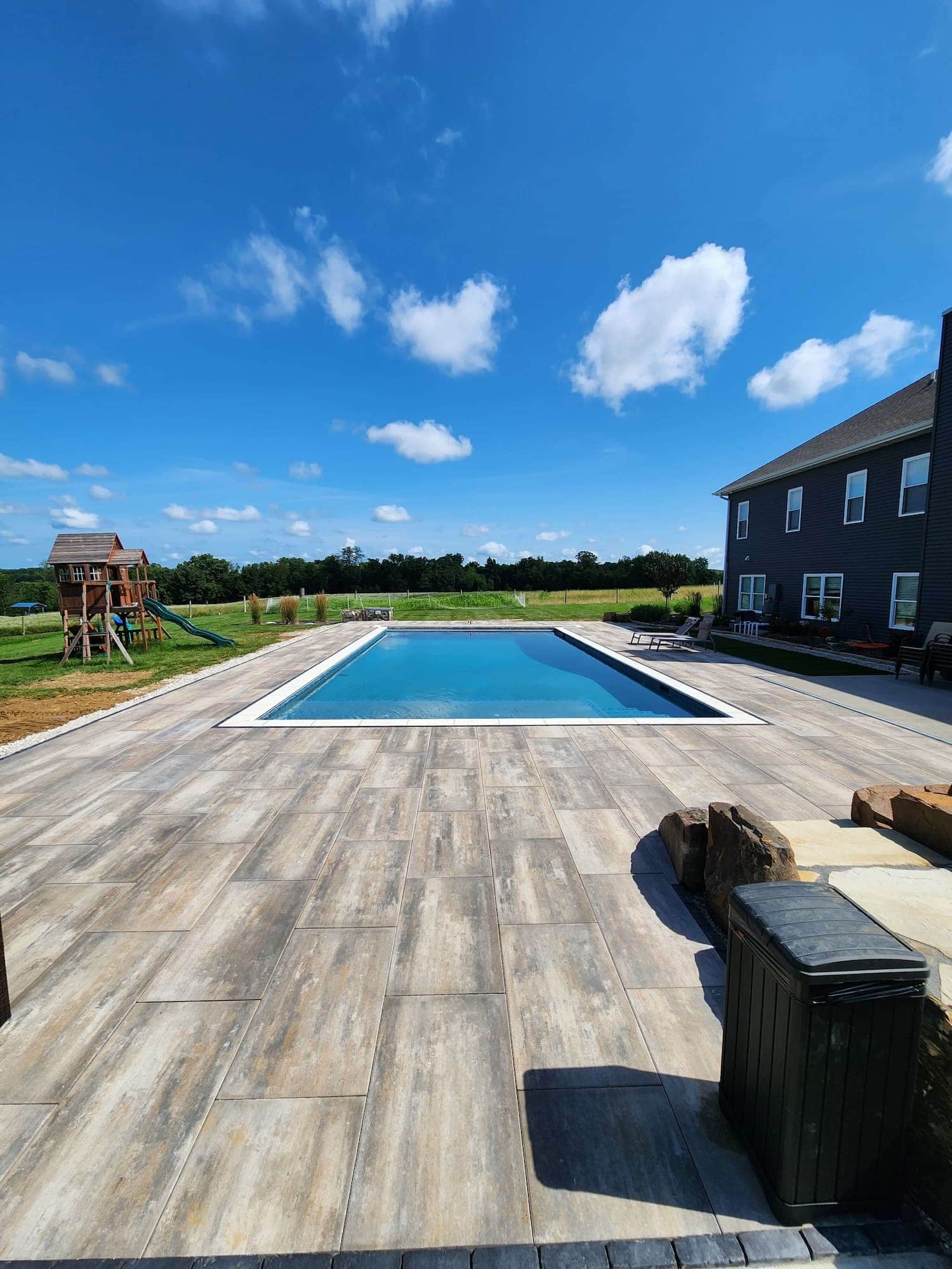 Outdoor Pool Surrounded by Tile and Blue Sky and Country Fields